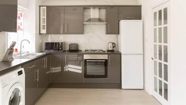 A modern kitchen with stainless steel appliances, a built-in oven, and a dishwasher. - Immaculate 2-bed House in Dartford (Dartford)