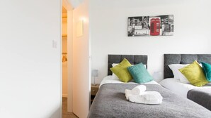 A hotel room with two beds, a wardrobe, and a wall with a black and white photo collage. - Immaculate 2-bed House in Dartford (Dartford)