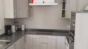 A kitchen with light wood cabinets, a black countertop, a built-in oven, and a white range hood. - 3 Bedroom (Sleeps 7) Villa in Carvoeiro (Carvoeiro)