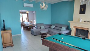 Un salón espacioso con mesa de billar, sofá modular y chimenea.