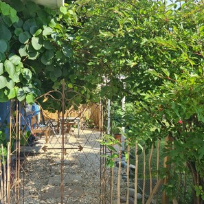 Un espace jardin agrémenté d’une clôture en métal, d’un chemin de gravier et de mobilier en bois.