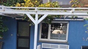 Een blauw gebouw met een witte bank en tafel onder een pergola.