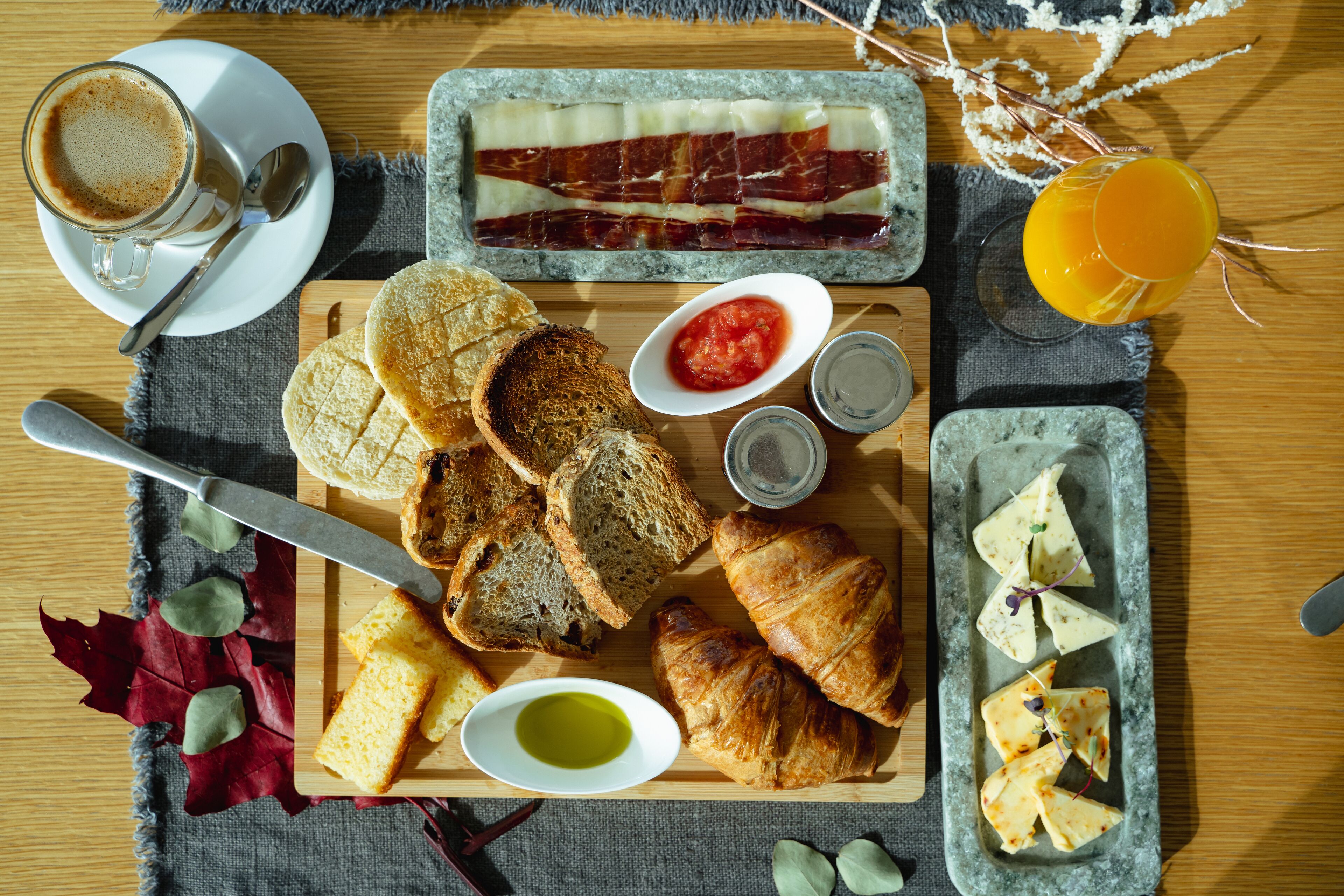 A breakfast spread with bread, croissants, cheese, and a coffee cup.