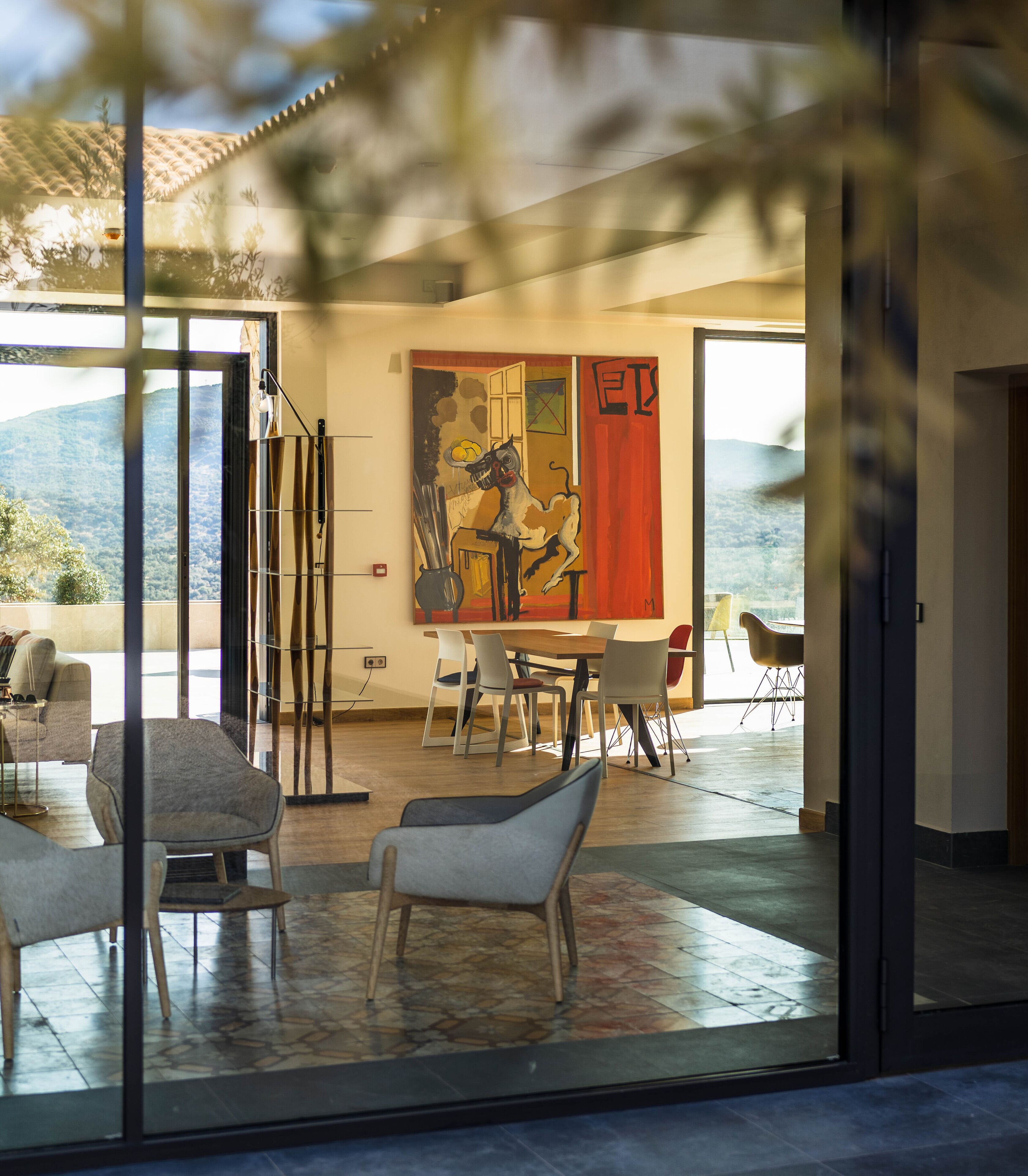 Um interior moderno com área de refeições, uma grande pintura abstrata e vista para o exterior.