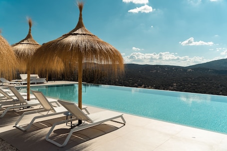 Una piscina al aire libre, sombrillas, sillones reclinables de piscina. Hoteles Desconecta2 by Vicoba