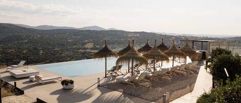 Una piscina al aire libre, sombrillas, sillones reclinables de piscina