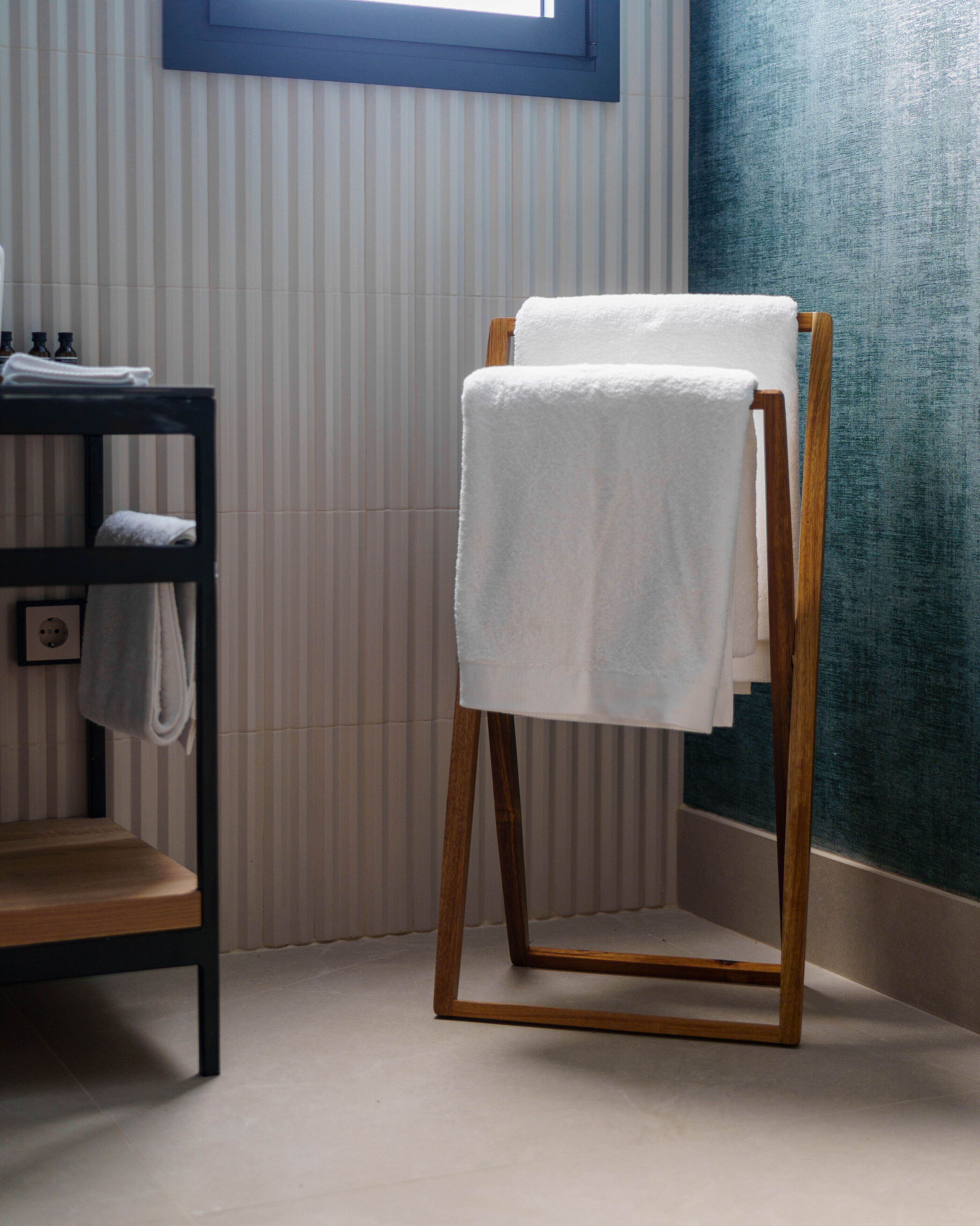 Un baño con un perchero de madera, un lavabo con una toalla y papel tapiz a rayas.
