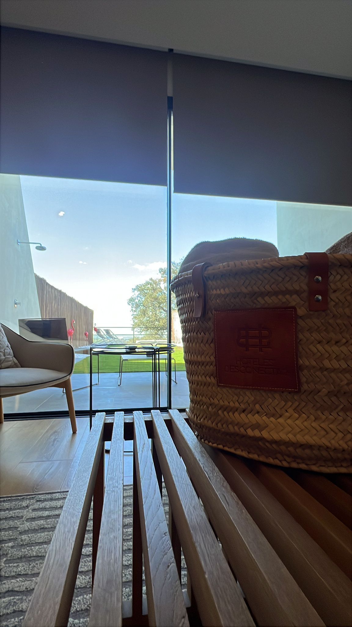A modern interior with a wicker basket on a wooden bench, a white sofa, and a view of the outdoors.