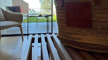 A modern interior with a wicker basket on a wooden bench, a white sofa, and a view of the outdoors.