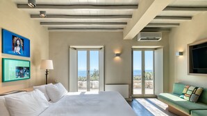 Ein Hotelzimmer mit einem großen Bett, einem grünen Sofa und Meerblick.