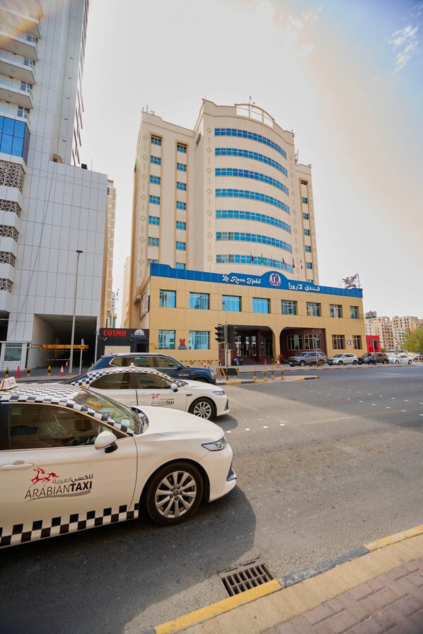 A building with a curved facade, multiple windows, and a sign indicating it is a hotel.