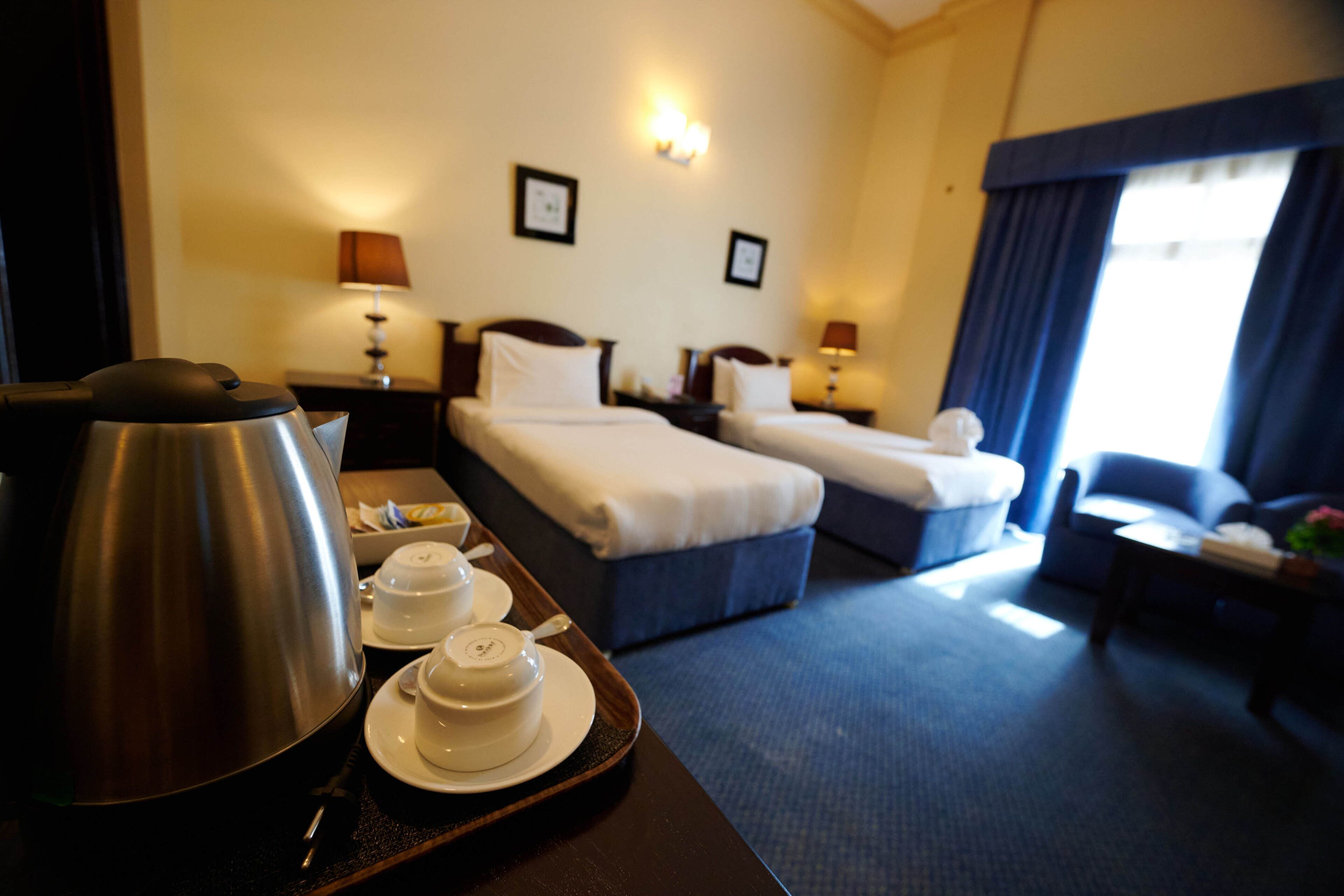 Ein Hotelzimmer mit zwei Betten, einer Kaffeemaschine, Tee-Set und Blick auf die Stadt.