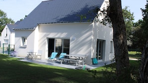 A modern house with a patio area featuring a table and chairs. - Maison, 5mn de Plage Lanséria, 4 à 10 Personnes (Mesquer)
