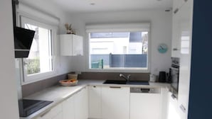 A modern kitchen with white cabinetry, a black countertop, a window, and a sink. - Maison, 5mn de Plage Lanséria, 4 à 10 Personnes (Mesquer)