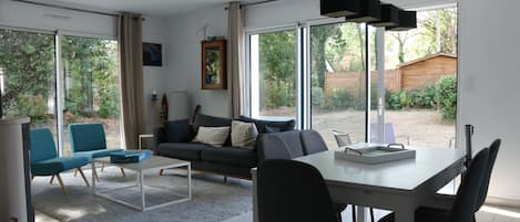 A modern living room with a sofa, chairs, a coffee table, and a dining table.