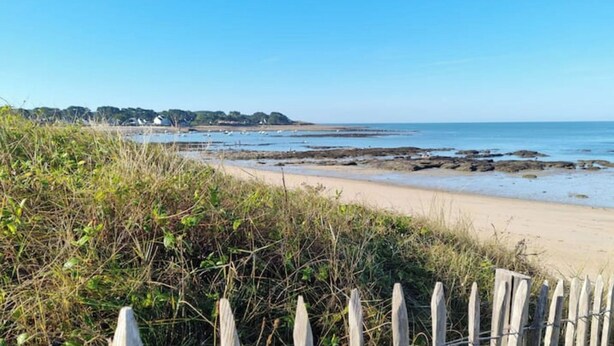 A beach with a wooden fence in the foreground, a sandy shore, and a clear blue sky. - Maison, 5mn de Plage Lanséria, 4 à 10 Personnes (Mesquer)