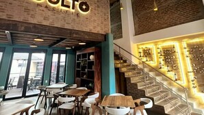 A restaurant interior with a brick wall, wooden tables, and a staircase leading to a bar area. - R1/ Artistic loft in La Candelaria (Bogotá)