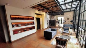 A spacious living area with a high ceiling, exposed beams, and a large window. - R1/ Artistic loft in La Candelaria (Bogotá)