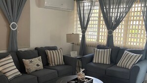 A living room with two grey sofas, a small coffee table, and a ceiling fan. - Punta Salinas Oasis (Toa Baja)