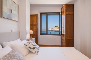 Relax in this serene hotel room featuring a large bed, nightstand, and stunning coastal views.