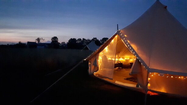 A tent with a simple interior layout, including a seating area and a table. - Rowan 6m xl Bell Tent (Saltburn-by-the-Sea)