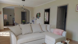 Una sala de estar con un sofá seccional color beige, una mesita blanca y un adorno de pared.