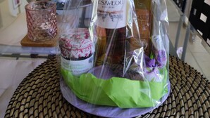 Una botella de vino en una bolsa de plástico transparente con una etiqueta, sobre un tapete tejido.