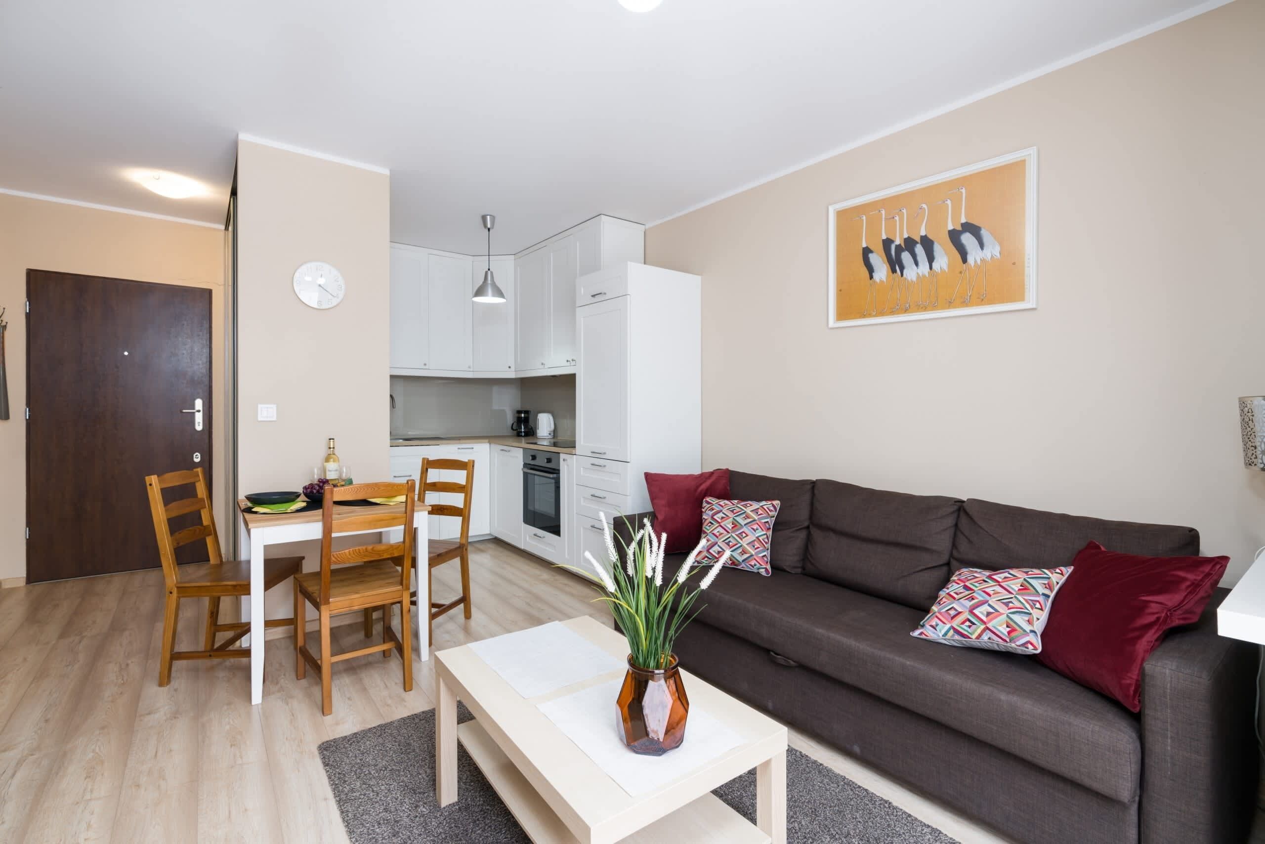 A cozy living room with a dark sofa, a wooden coffee table, and light-colored walls, decorated with modern artwork.
