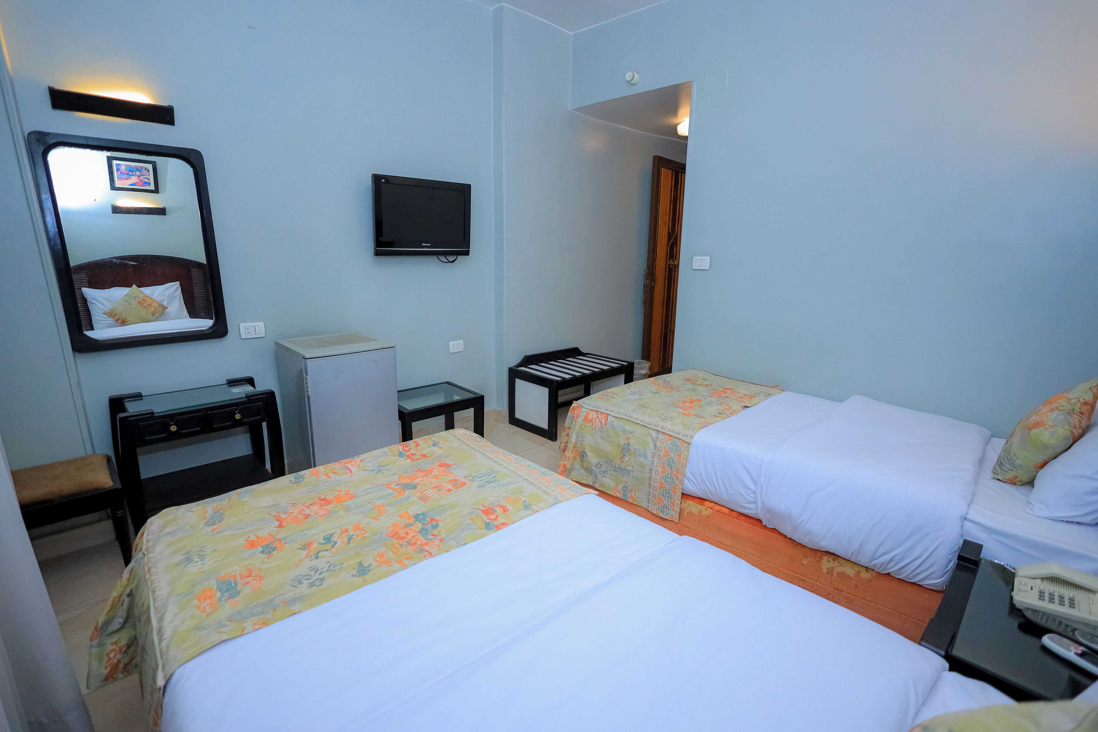 A hotel room with two beds, a television, a desk, and a small table.