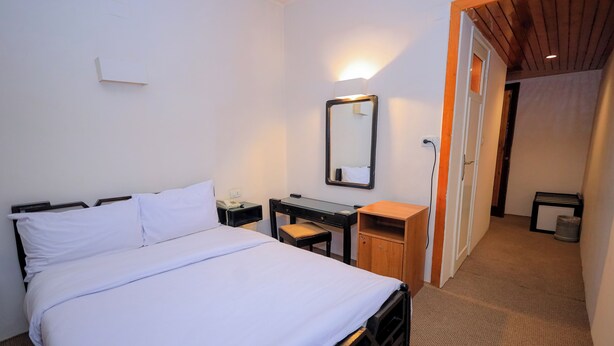 A hotel room with a bed, a desk, a chair, a mirror, and a door leading to another room. - Cleopatra Hotel (Aswan)