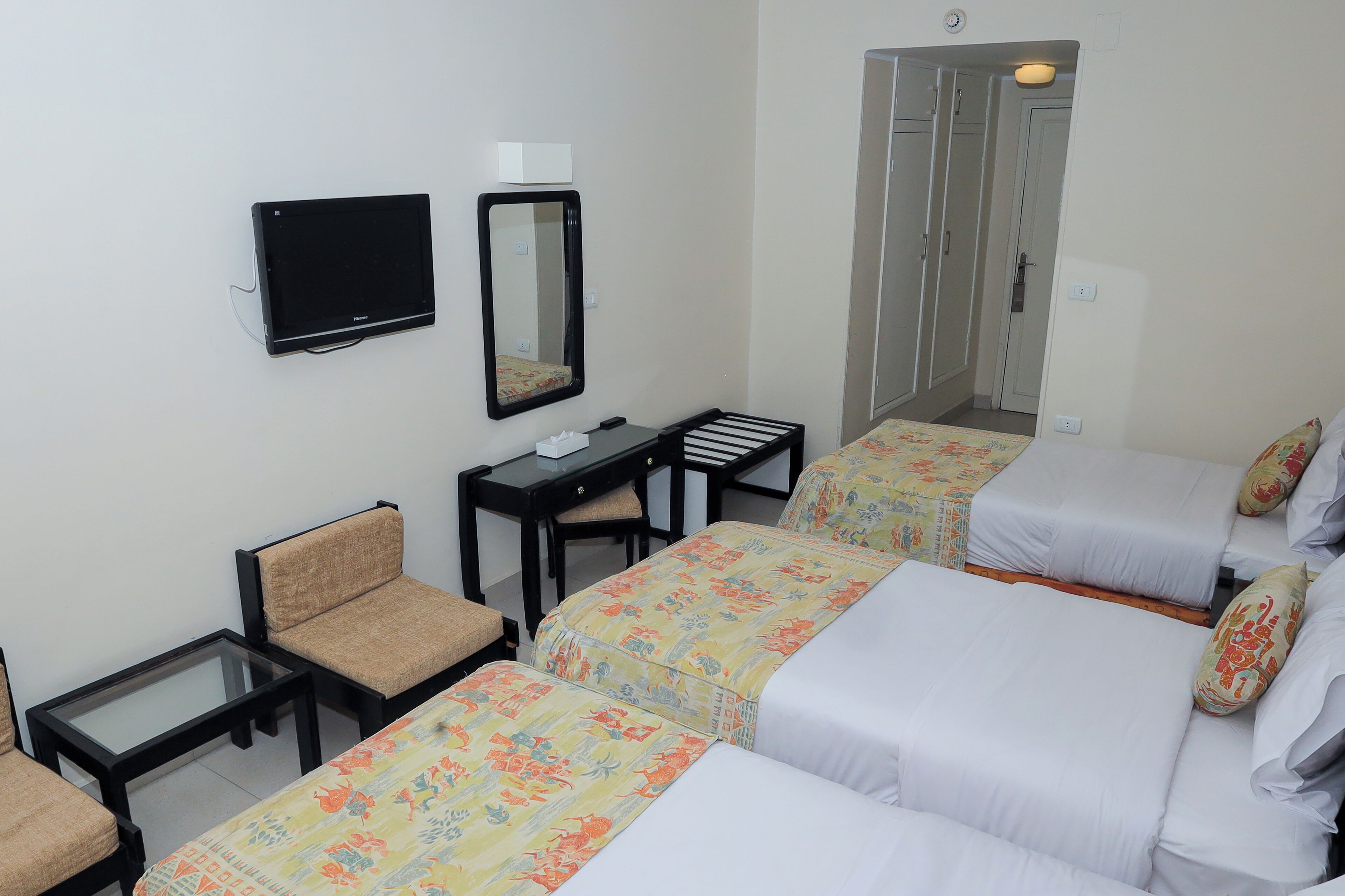 Habitació d'hotel amb dos llits individuals, una taula de treball amb cadira, televisió i mirall.