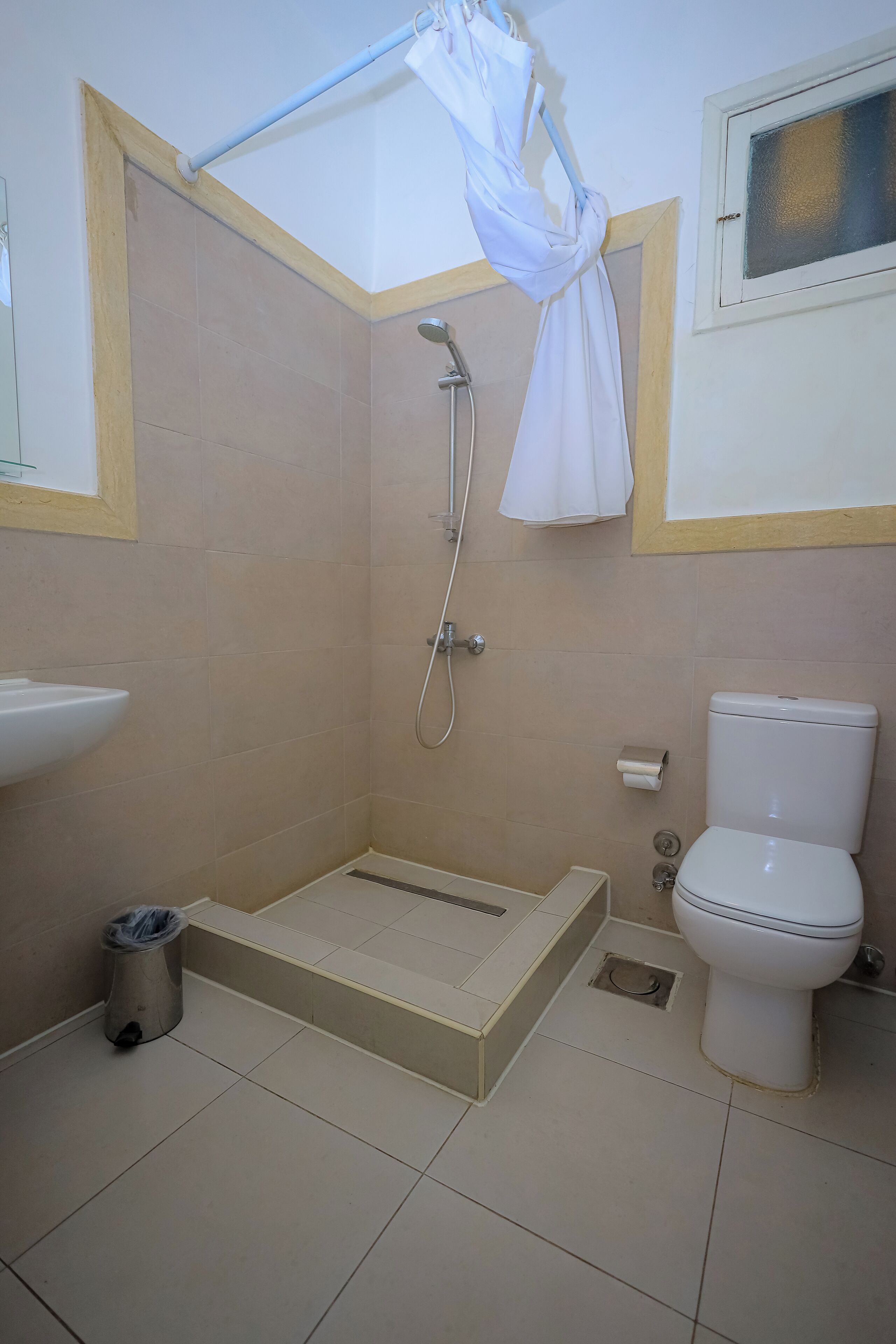 Bagno con doccia, WC, lavandino e cestino.