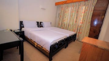 A bedroom with a bed, a desk, and a wooden headboard.