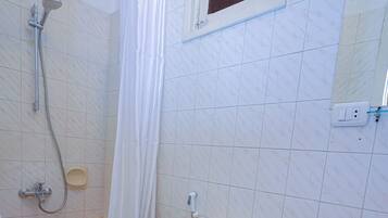 Un baño con inodoro, lavamanos, ducha y una ventana pequeña.