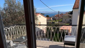 A balcony with a metal railing, a cushioned bench, and a small table. - Charming new House on Islandfew Steps From the sea (Kali)