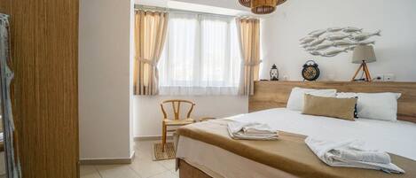 A hotel room with a large bed, a wooden headboard, a window with curtains, a bedside table with a lamp, and a wall clock.