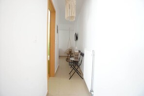 A hallway with a dining area featuring a table and chairs, a hanging macrame light fixture, and a radiator on the wall. - Urban beach sun(1c) The ultimate urban beach vibe. (Rethymno)
