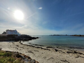 A coastal scene with a house by the sea, clear skies, and calm waters.