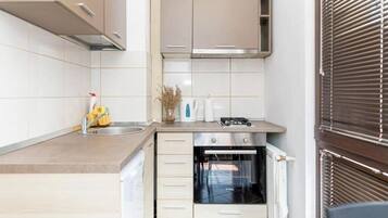 Een koelkast, een oven, een broodrooster, kookgerei, borden en bestek