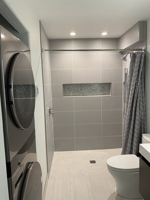 A modern bathroom with a shower, toilet, and a built-in circular mirror.
