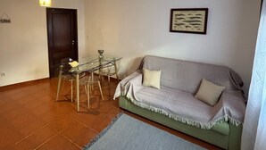 A living room with a sofa, a glass table with chairs, a hanging light fixture, and a framed picture on the wall. - Almograve House (Almograve)