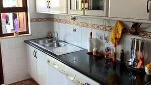 A compact kitchen with a built-in washing machine, a sink, and a stove. - Almograve House (Almograve)