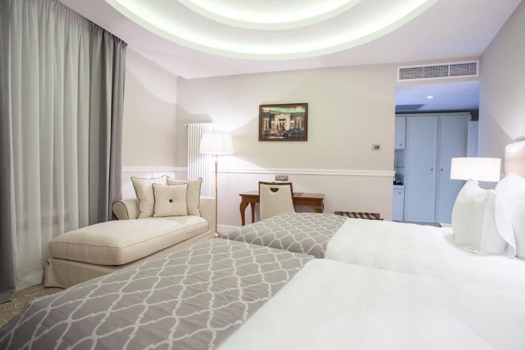 A hotel room with a bed, a sofa, a desk, and a chair.