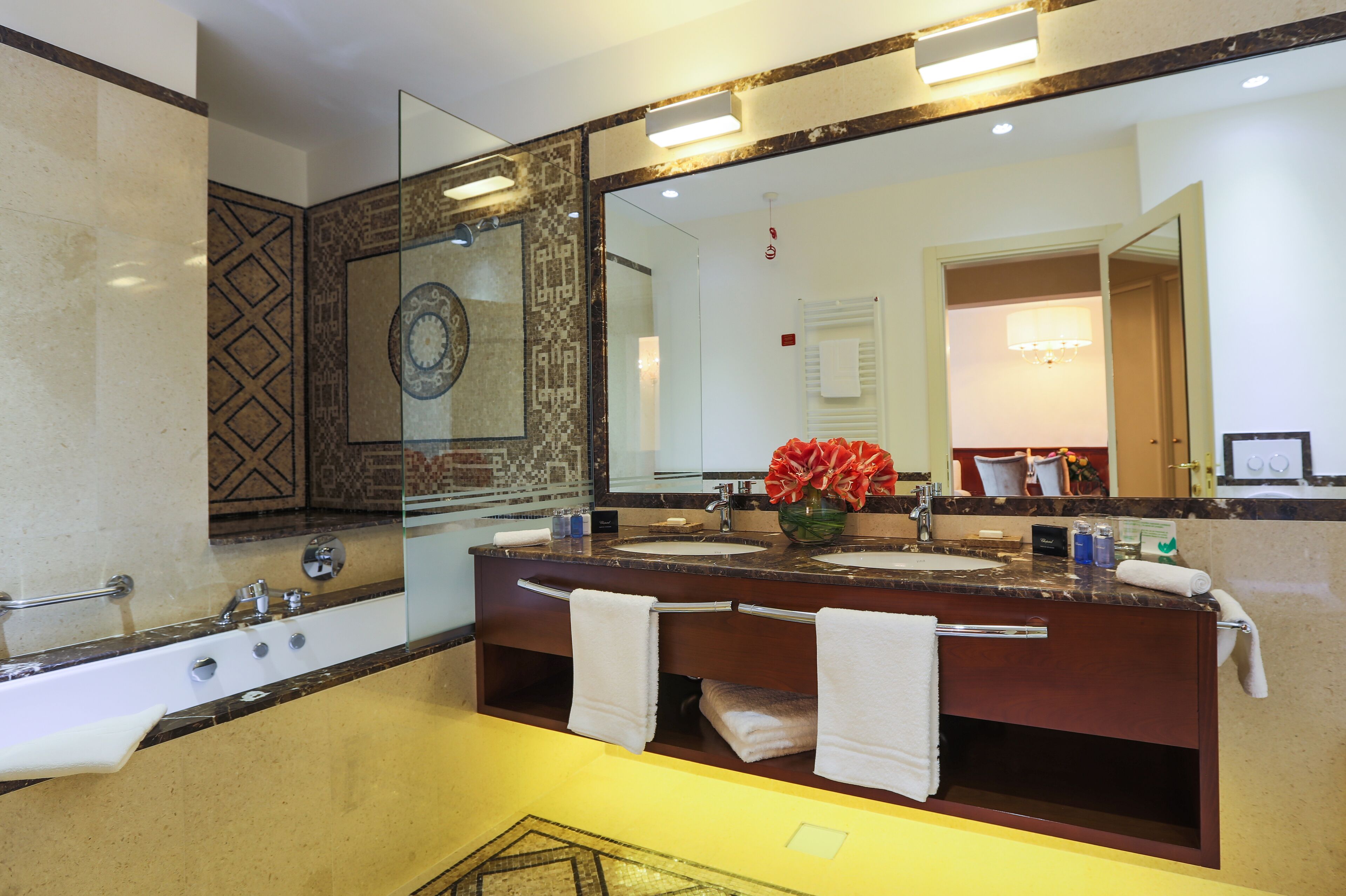 Une salle de bain avec un grand miroir, deux lavabos et une baignoire.