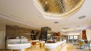 Un hall d’hôtel moderne comprenant un comptoir d’accueil, un espace salon et un plafond décoratif.