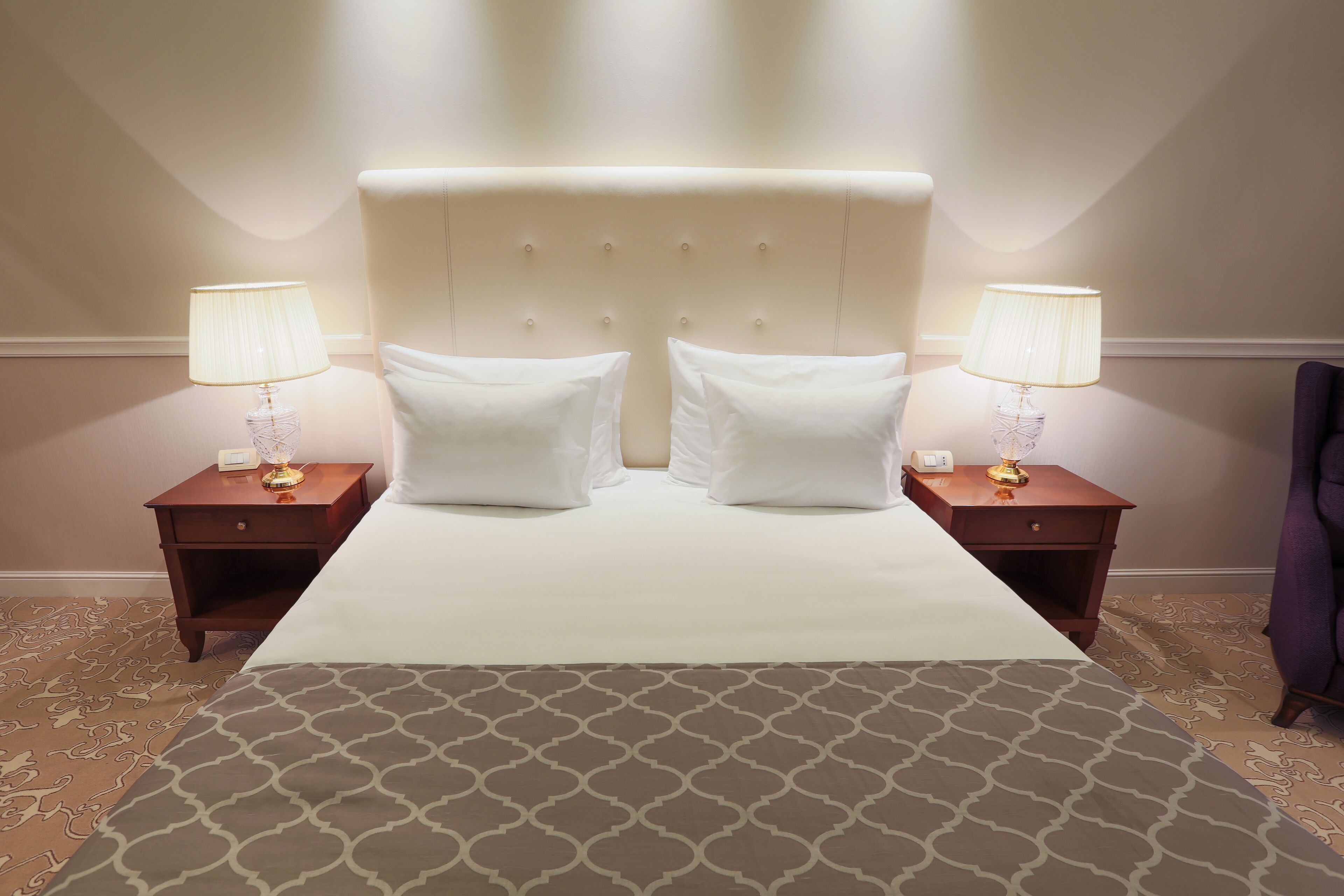Una camera d'albergo con un letto grande, due comodini e lampade.