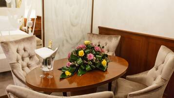 A round wooden table with a floral centerpiece and two champagne flutes.