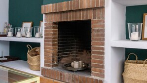 A brick fireplace with a white mantel, surrounded by shelves with various items.