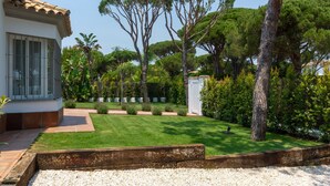 A well-maintained garden with a lawn, trees, and a white structure.