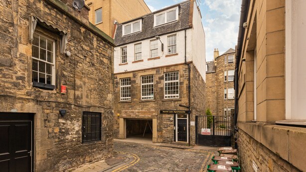 A narrow street with stone buildings, a sign for 'North Lane Apartments', and a gated entrance. - Amazing Castle View Apartment (Edinburgh)